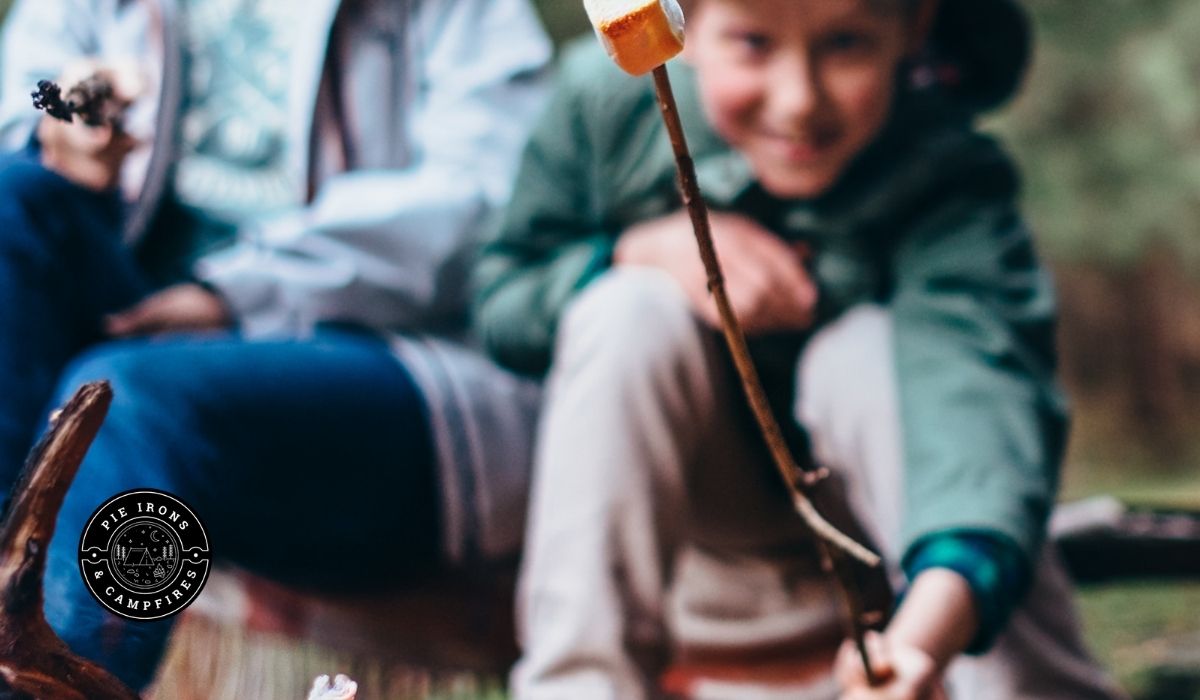 Boy holding marshmallow over campfire and Tips for family Camping @ PieIronsAndCampfires.com