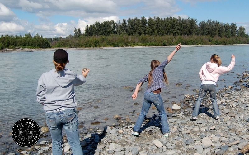family skipping rocks on the water